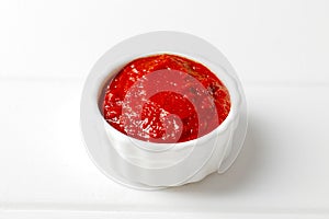 tomato sauce in a small white gravy boat on a white wooden