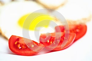 Tomato slice in the fried eggs close