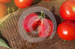 Tomato with slice on rustic wooden background. Fresh cut tomato  on wooden table