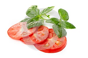 Tomato slices with basil leaves on a white background