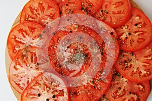Tomato slices sprinkled with spices and pepper close up. Food background