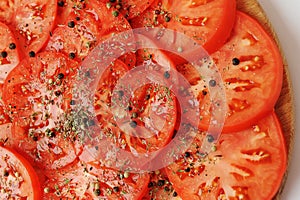 Tomato slices sprinkled with spices and pepper close up. Food background