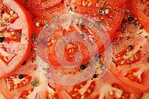 Tomato slices sprinkled with spices and pepper close up. Food background