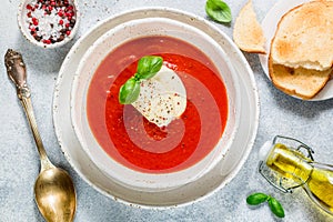 Tomato soup with mozzarella cheese, Basil and spices in a white plate. A thick, hearty dish, served with bread toast and olive oil