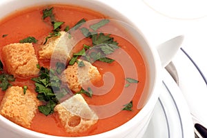 Tomato soup with croutons in bowl on white