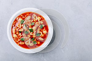 Tomato soup. Minestrone soup. Tomato bean and pasta soup bowl on gray stone background