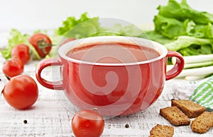 Tomato soup in red ceramic bowl on rustic wooden background. Hea