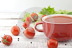 Tomato soup in red ceramic bowl on rustic wooden background. Hea