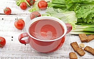 Tomato soup in red ceramic bowl on rustic wooden background. Hea