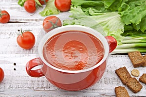 Tomato soup in red ceramic bowl on rustic wooden background. Hea