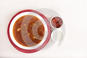 Tomato soup,  served with sour cream and extra tomato sauce,  white and red plate,  light background,  isolated