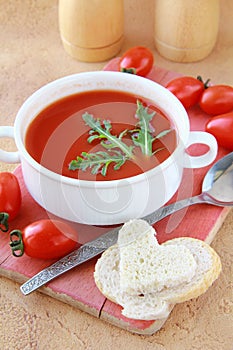 Tomato soup in a white bowl with arugula