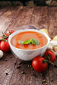 Tomato soup in a white bowl,tomatoes and parsley on a wooden background.