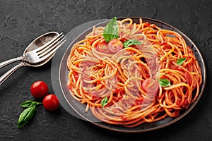 Tomato spaghetti on black plate on dark slate table. Tomato sauce pasta is classic italian cuisine dish. italian food