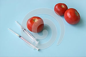 Tomato and syringe with GMO on a blue background