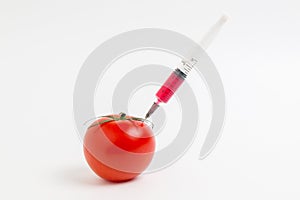 Tomato and syringe with nitrates. GMO food ingredient concept