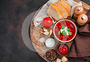 Tomato vegetable soup with fresh sour cream. Traditional borscht on a brown concrete background