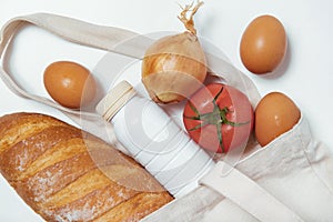 Tomato, white bread, white bottle, onion, eggs in tote bag on white background close textured