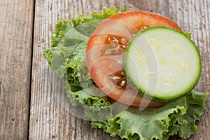 Tomato and zuchini slice on wood background, close-up