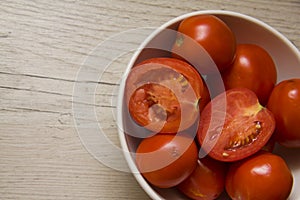 Tomatoes in a bowl on wooden background