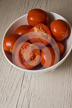 Tomatoes in a bowl on wooden background