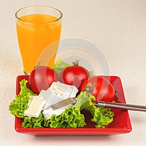 Tomatoes and cheese slices lie on a sheet of fresh salad in a re