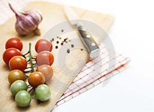 Tomatoes cherry with garlic and black pepper on the wooden board. Different degrees of ripeness of tomatoes cherry.