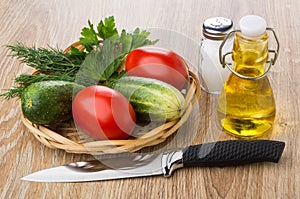 Tomatoes, cucumbers and greens in wicker basket, vegetable oil,