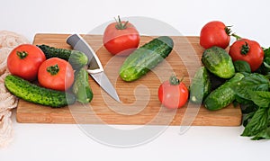 Tomatoes and cucumbers lying on a cutting board ready to be cut