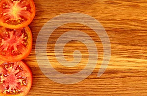 Tomatoes cut into pieces lie on the edge of a cutting board