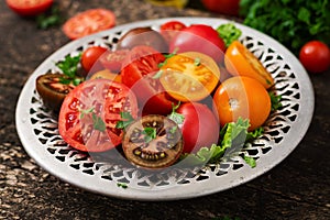 Tomatoes of different colors with green herbs