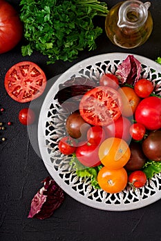 Tomatoes of different colors with green herbs