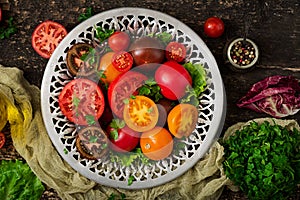 Tomatoes of different colors with green herbs in a bowl