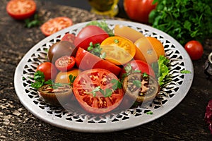 Tomatoes of different colors with green herbs