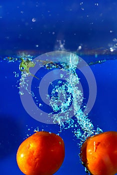 Tomatoes drop water spurting on background