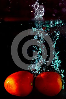 Tomatoes drop water spurting on background