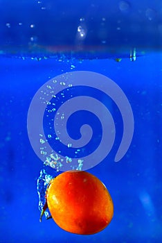 Tomatoes drop water spurting on background