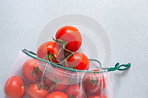 Tomatoes in eco-friendly packaging. Reusable bags for vegetables and fruits. Shopping in the store, retail. Eco-friendly packaging