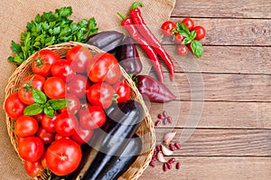 Tomatoes, eggplants in basket and other vegetables on sacking an