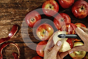 Tomatoes in female hands. Woman peeling an apple in the kitchen