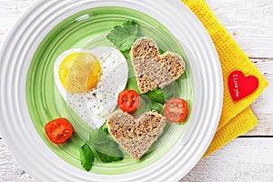 Tomatoes, fried egg and bread in the shape of a heart. Romantic food Valentine day Breakfast with a red heart