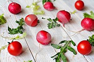 Tomatoes, garden radish, lettuce leaves, arugula, fennel and parsley on a wooden background.