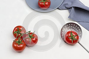 Tomatoes on green branch. Tomato and allspice on gray plate. Tomato with green tail on skimmer