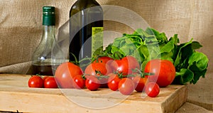 Tomatoes, green salad, olive oil bottle and vinegar transparent bottle