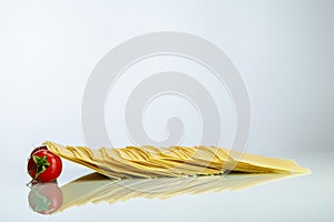 Tomatoes sustaining lasagna row on white reflexive glass