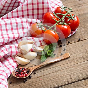 Tomatoes, mint, garlic and pepper on dark wood and dish towel