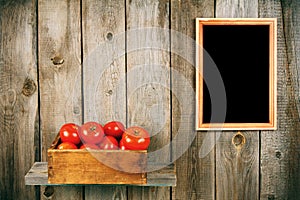 Tomatoes in an old box on a wooden shelf.