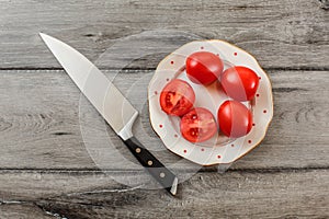 Tomatoes, one of them cut in half on white porcelain plate with
