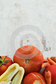 Tomatoes, pepper and carrots on wooden board