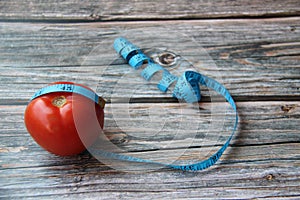 Tomatoes, red, fresh and organic with a tape measure on an old wooden table.